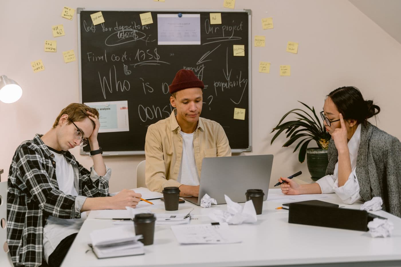Drei junge Menschen planen ein Projekt mit Notizen und Laptop